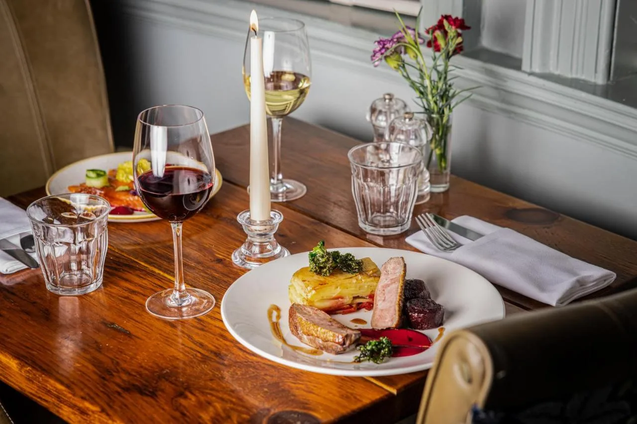 A wooden table with two plates of food and wine glasses at Lansdown Grove Hotel in Bath
