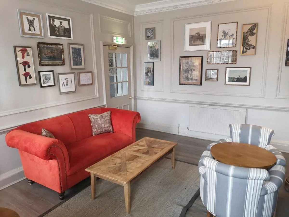 A living room with a red couch and a table at Lansdown Grove Hotel in Bath
