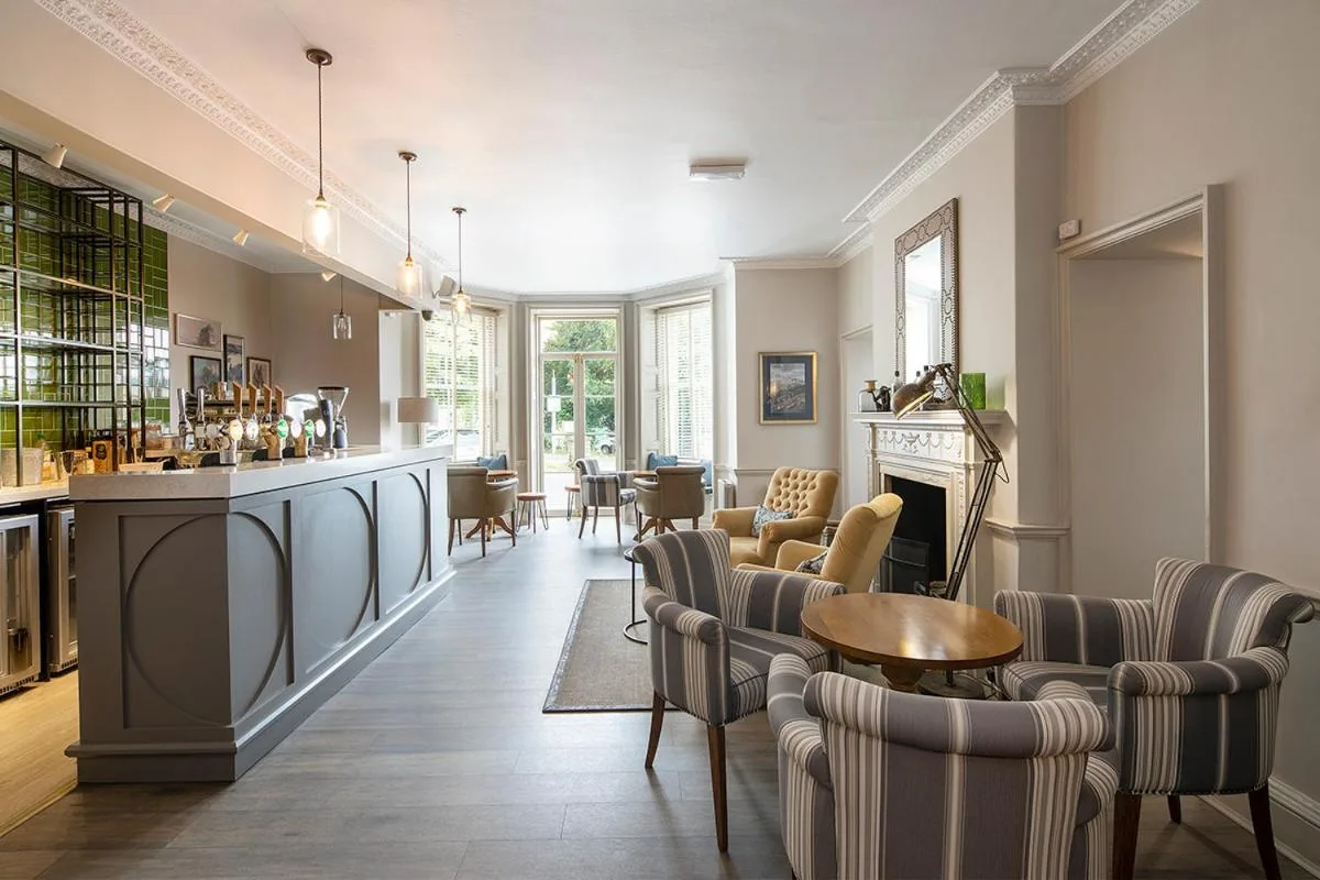 A living room with chairs, a table and a bar at Lansdown Grove Hotel in Bath